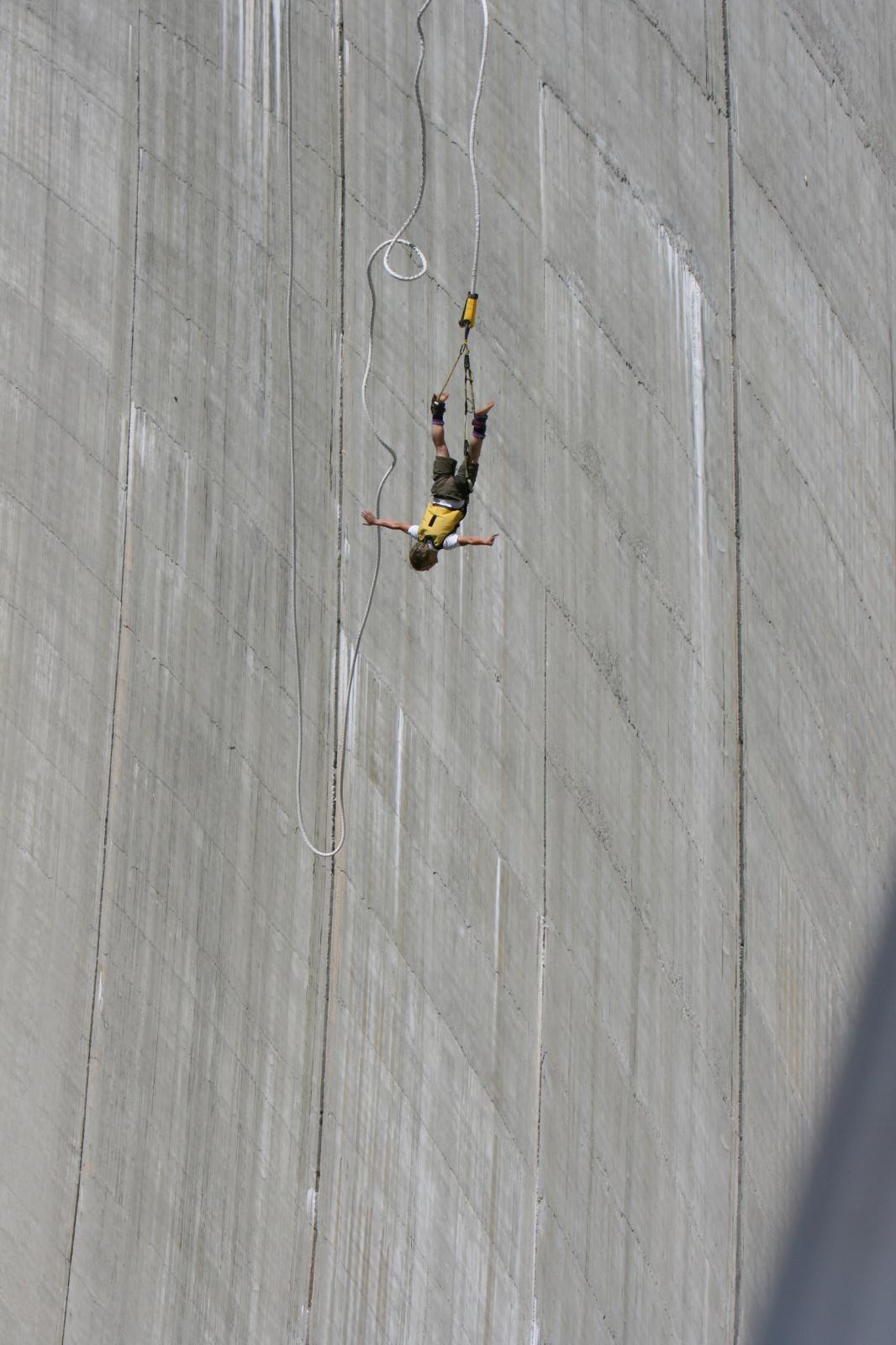 Erleben Sie den ultimativen Nervenkitzel beim Bungee-Jumping im Verzascatal, wo Sie sich frei wie ein Vogel fühlen können. Das Bild zeigt eine Pererson im freiehn Fall an der Staumauer entlang am Bungee-Jumpingseil