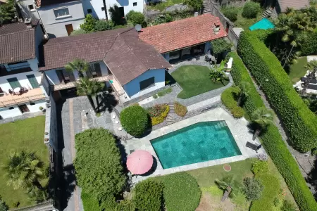 Die Drohnen-Luftaufnahme des Ferienhauses Casa Ramerino in Brissago zeigt ein beeindruckendes Bild. Das Schwimmbad fügt sich perfekt in die Umgebung ein